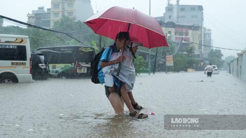 Người dân dậy sớm đi làm, phụ huynh cõng con qua đoạn ngập ở Hà Nội