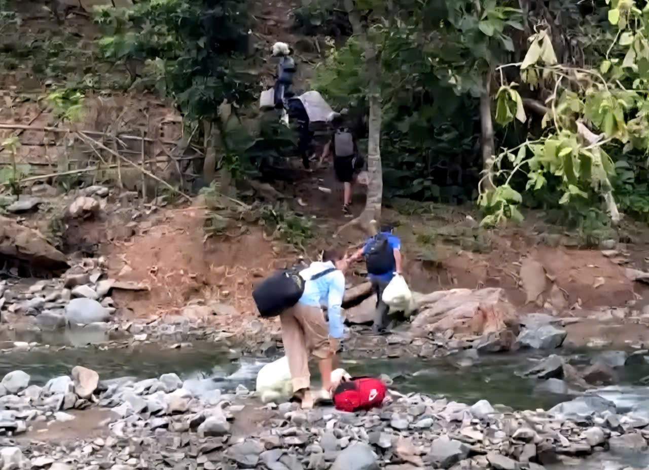 Các thầy cô giáo vác lương thực, thực phẩm qua suối để tiếp tế cho học sinh Trường phổ thông dân tộc bán trú Tiểu học và THCS Kim Bon. Ảnh: Nguyễn Trường