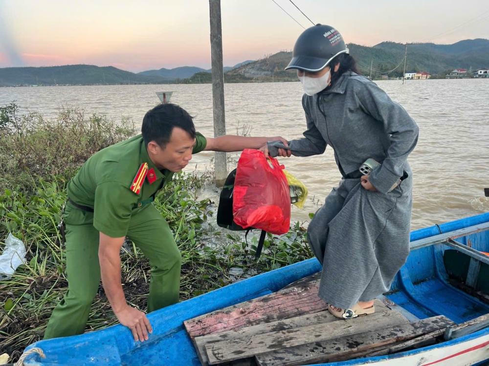Chiến sĩ công an xã Nghi Xuân đưa chị Hạnh lên thuyền ra khỏi vùng lũ cô lập. Ảnh: CAHT