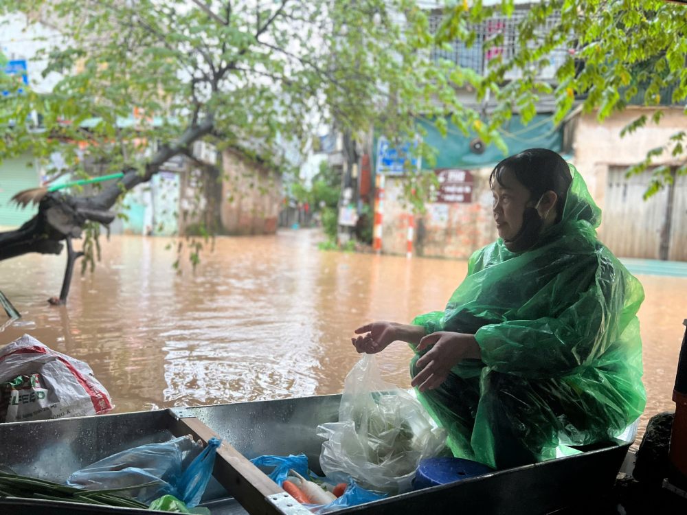 Phố Cầu Cốc ngập sâu, chị Thảo dùng thuyền để bán hàng. Ảnh: Ngô Cường
