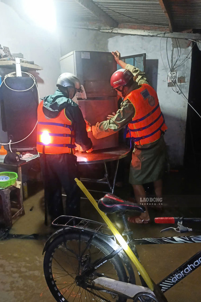 Lực lượng chức năng xã Phù Mỹ hỗ trợ người dân có nhà bị ngập kê đồ đạc lên cao. Ảnh: Hoài Phương