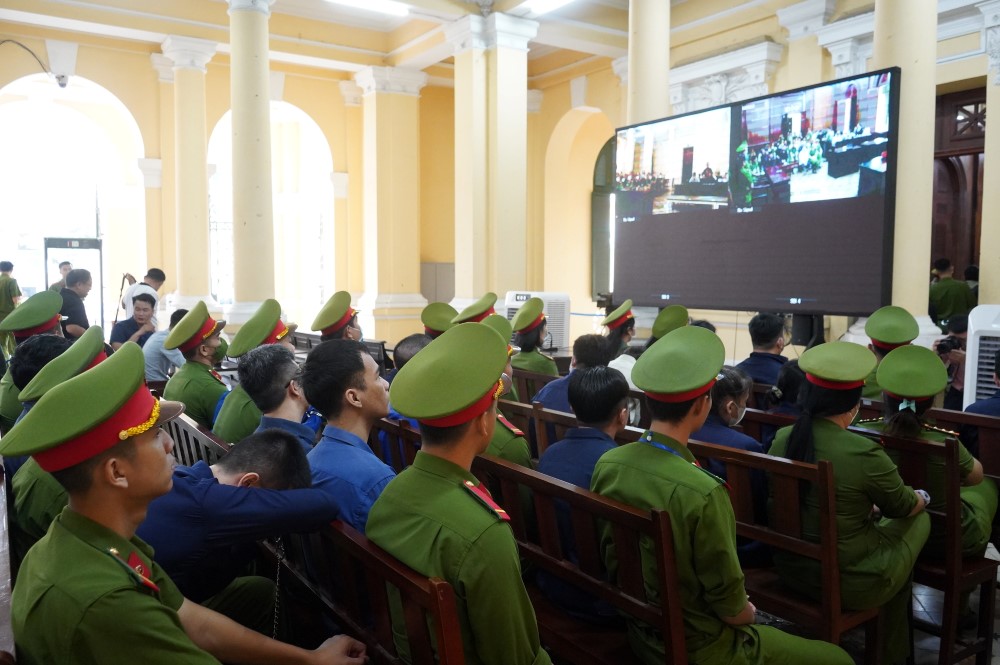 Do số lượng bị cáo nhiều nên tòa lắp thêm máy chiếu để các bị cáo theo dõi.  Ảnh: Anh Tú