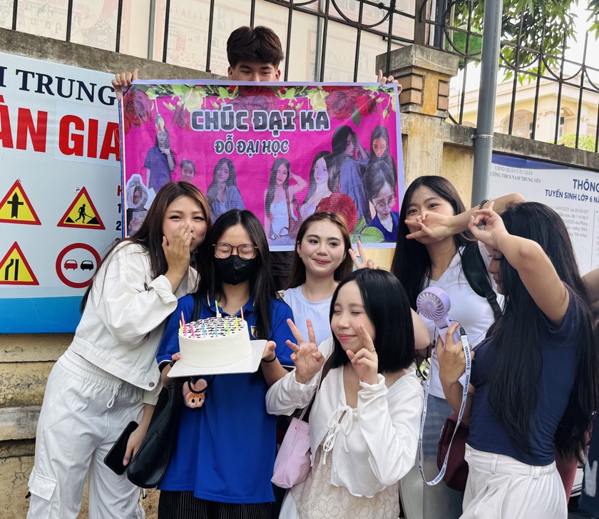 Một thí sinh được bạn mang bánh và khẩu hiệu đi cổ vũ tại điểm thi Trường THCS Nam Trung Yên (Hà Nội).