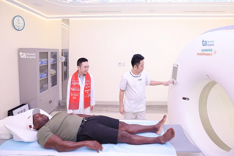 Danh thủ Dwight Yorke trải nghiệm chụp siêu máy CT Somatom Force VB30 ứng dụng AI đầu tiên tại Việt Nam để tầm soát các chấn thương tiềm ẩn. Ảnh: BVĐK Tâm Anh