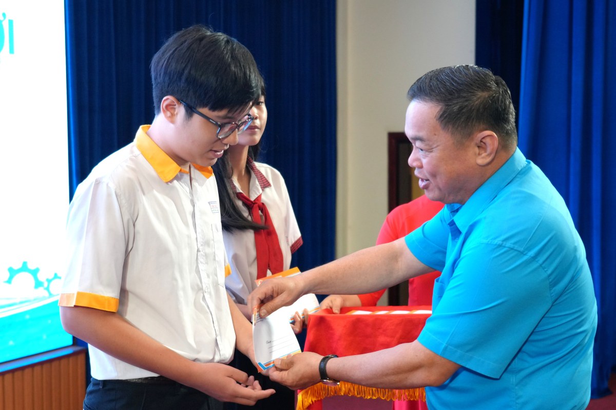Ông Nguyễn Bá Hùng - Phó Chủ tịch LĐLĐ TPHCM - trao học bổng Nguyễn Đức Cảnh cho các em học sinh. Ảnh: Thành An