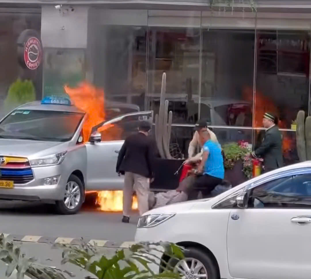 Nhân viên khách sạn và người dân tập trung dập lửa cứu tài xế mắc kẹt trong taxi. Ảnh: Cắt từ clip