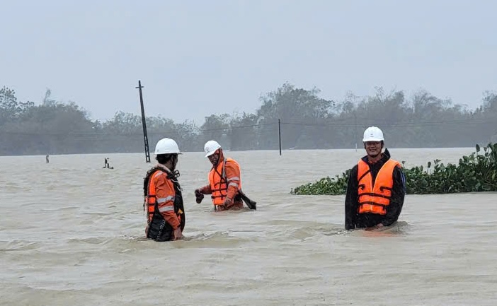 Công nhân điện lực Huế lội lũ khắc phục sự cố đảm bảo cấp điện trở lại. Ảnh: N. Huyền.