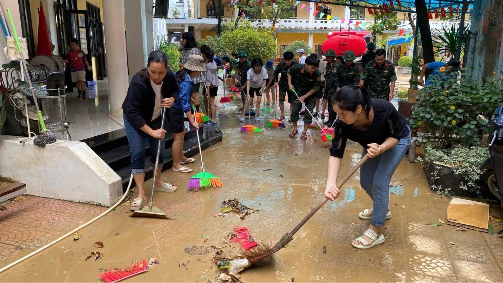 Bộ đội, giáo viên cùng phụ huynh chung tay dọn dẹp trường học sau lũ. Ảnh: Phúc Đạt