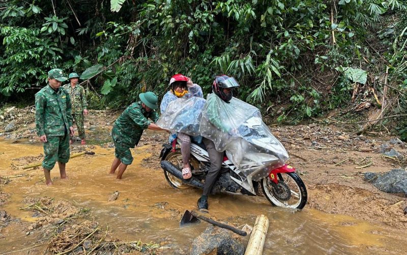 Hỗ trợ người dân di chuyển qua đoạn đường đầy bùn đất sau đợt mưa lớn. Ảnh: H.Nguyên