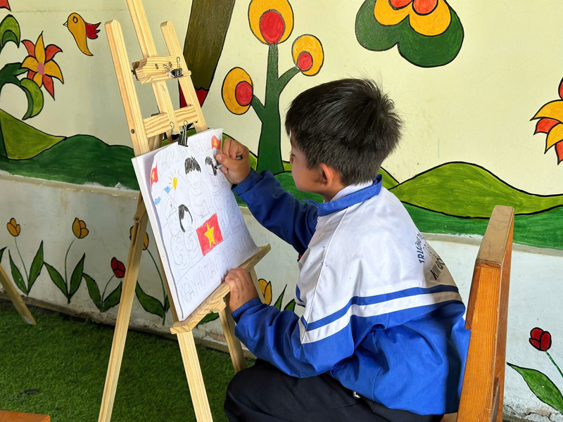 Một bạn nhỏ say sưa vẽ, thể hiện bức tranh về ngày hội bầu cử. Ảnh: Nguyễn Dương