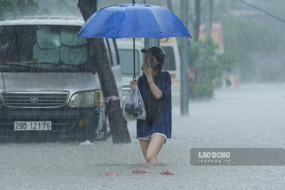 Người dân lội nước di chuyển qua đoạn ngập. Ảnh: Sóng Hữu