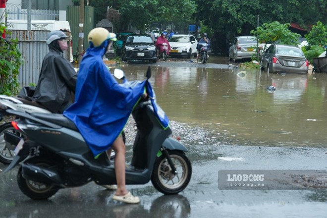 Người dân dậy sớm đi làm, phụ huynh cõng con qua đoạn ngập ở Hà Nội